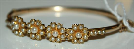 Yellow metal and seed pearl floral-mounted hinged bangle (tests as 14ct gold)